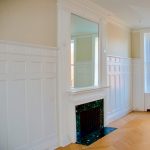 High raised-panel wainscoting surrounding a fireplace in a formal room