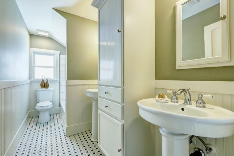 Remodeled bathroom with two pedestal sinks, tub toilet, black and white floor tile