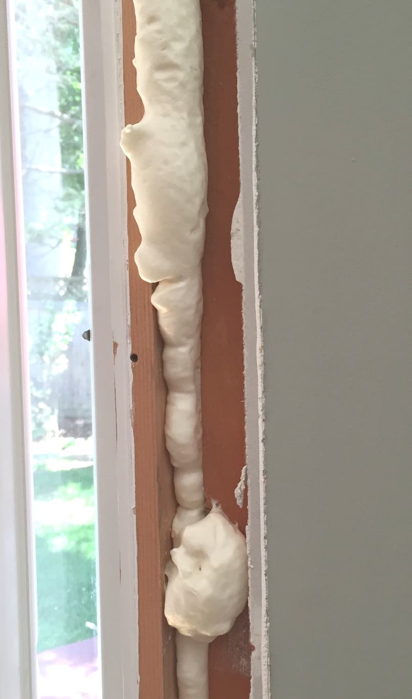 Expanding foam insulation filling the gap between rough framing and the window jamb