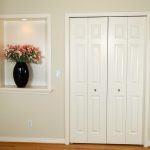 Pair of closet doors and adjacent wall niche with trim around them.
