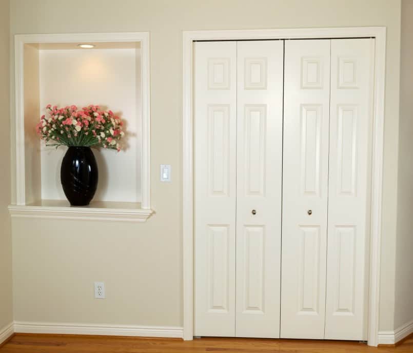 Pair of closet doors and adjacent wall niche with trim around them.