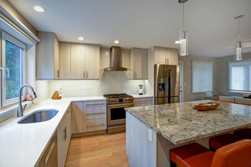 View of modern kitchen with island, counter lighting, tile backsplash and recessed lights.